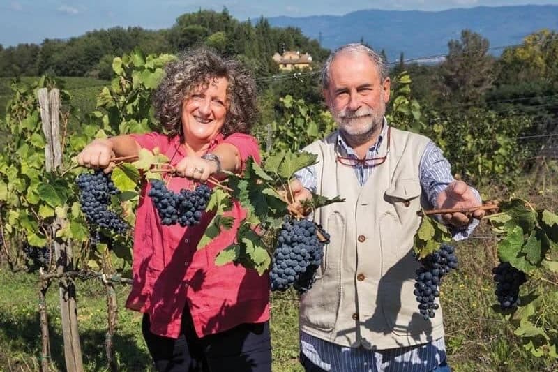 Chez nos vignerons, en Italie : deux vignerons présentent des grappes de raisin dans leurs vignes